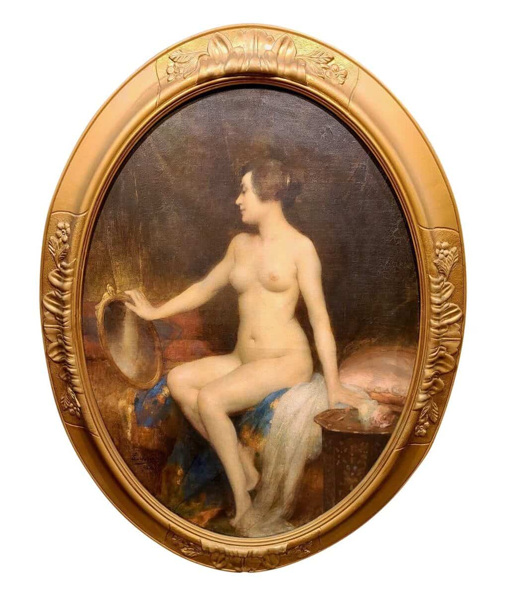 Femme nue assise sur un pan de lit se contemple dans un petit miroir doré.