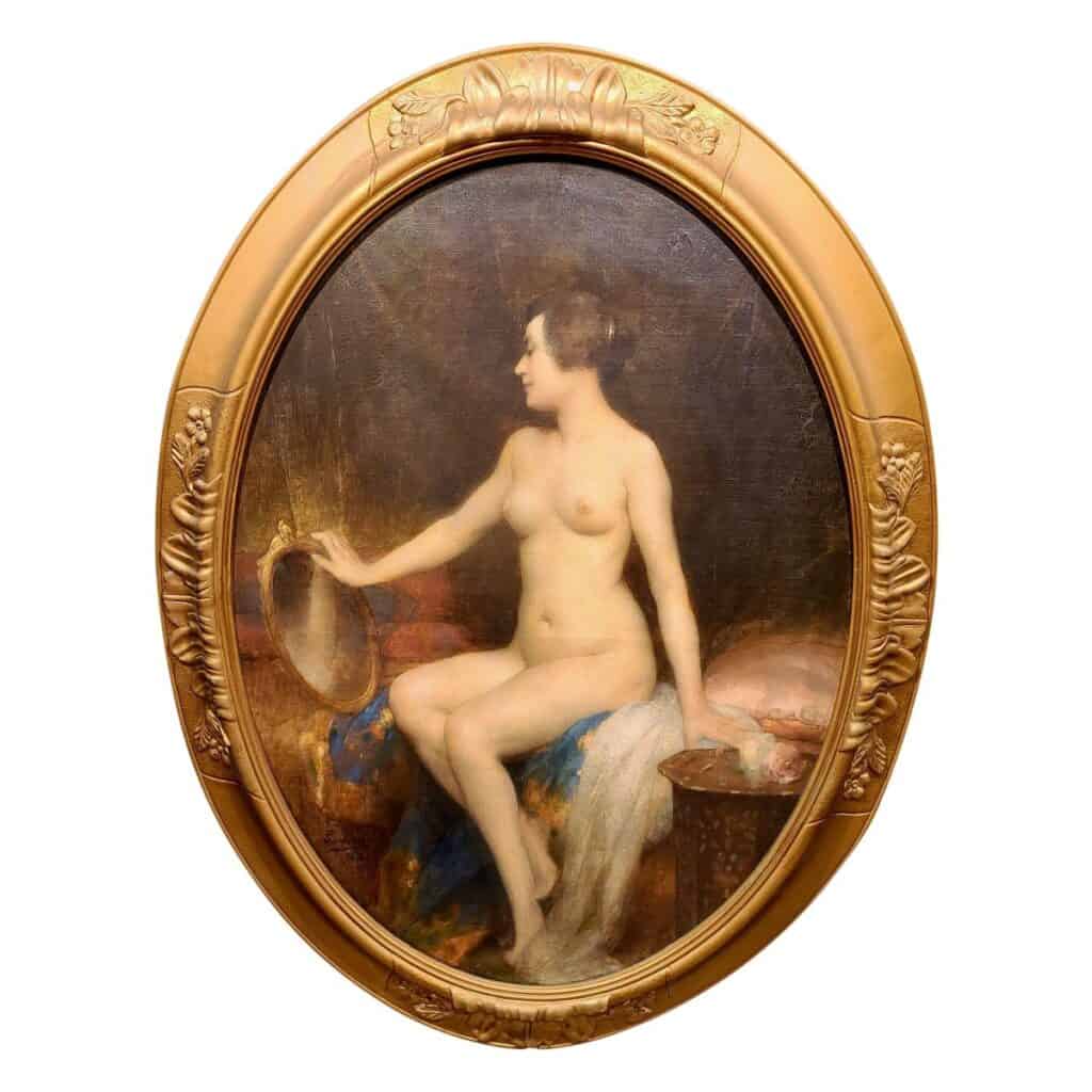 Femme nue assise sur un pan de lit se contemple dans un petit miroir doré.