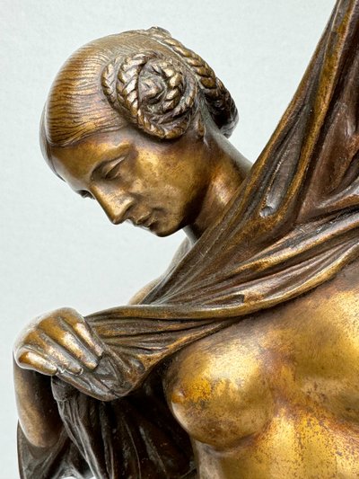 Scultura in bronzo raffigurante una donna seduta che si spoglia