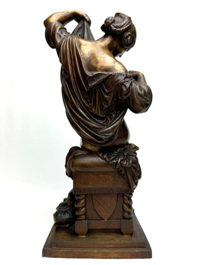 Scultura in bronzo raffigurante una donna seduta che si spoglia