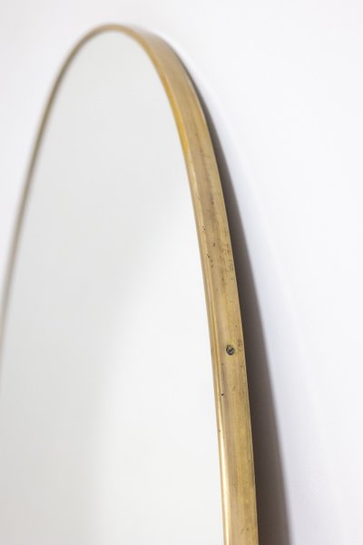 Specchio di forma ovale con asta in ottone dorato. Anni '70. Modello LS6260509U