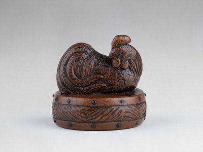 Netsuke di Tametaka. Modello in legno raffigurante un gallo appollaiato su un tamburo. Edo Giappone
