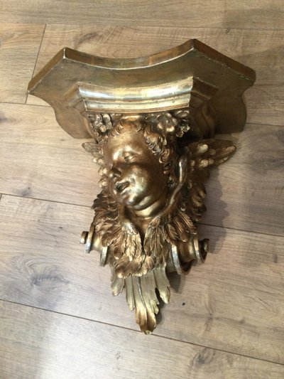 Une console murale en bois doré à tête d'angelot.