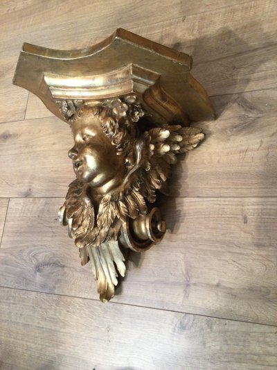 Une console murale en bois doré à tête d'angelot.