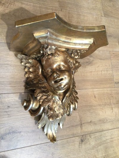 Une console murale en bois doré à tête d'angelot.