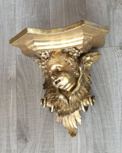 Une console murale en bois doré à tête d'angelot.
