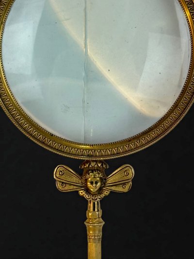 LARGE EMPIRE PERIOD MAGNIFYING GLASS IN CHASED AND GILDED BRONZE WITH WINGED FEMALE HEAD DECORATION