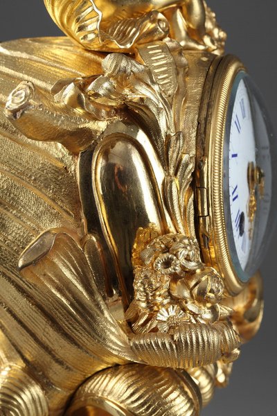 Pendule de style Rocaille en bronze doré, ornée d'un Amour dans une coquille