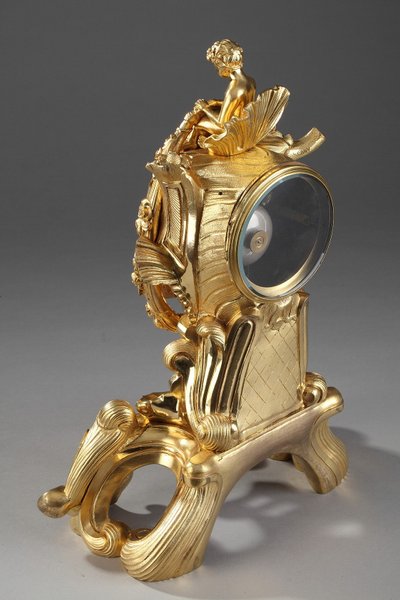 Pendule de style Rocaille en bronze doré, ornée d'un Amour dans une coquille