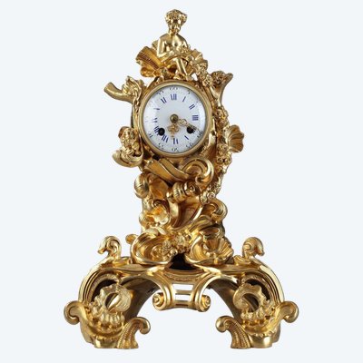 Pendule de style Rocaille en bronze doré, ornée d'un Amour dans une coquille