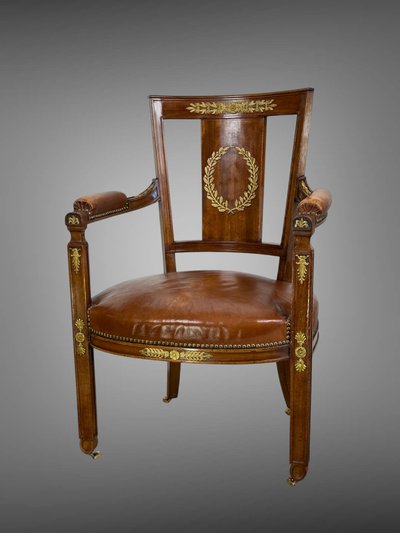 Empire-style armchair in walnut decorated with gilt bronze and covered in brown leather