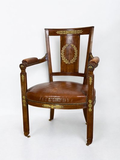 Empire-style armchair in walnut decorated with gilt bronze and covered in brown leather