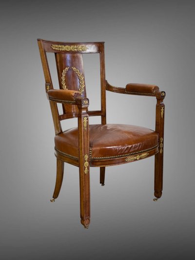 Empire-style armchair in walnut decorated with gilt bronze and covered in brown leather
