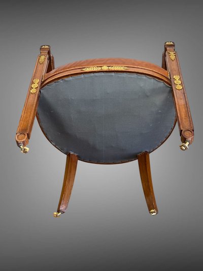 Empire-style armchair in walnut decorated with gilt bronze and covered in brown leather
