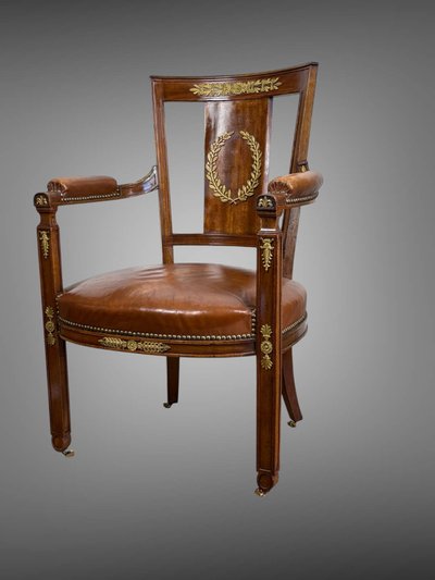 Empire-style armchair in walnut decorated with gilt bronze and covered in brown leather