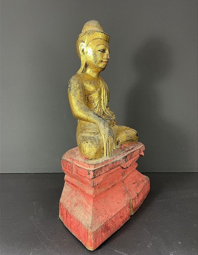 Birma, Mitte des 20. Jahrhunderts, rot und gold lackierte Holzskulptur, die einen sitzenden Buddha darstellt.