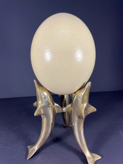 France, Ostrich egg mounted on a brass tripod base with a representation of dolphins, 1970.