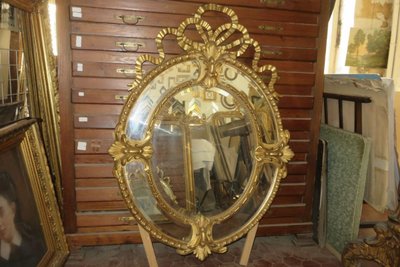 Grande specchio ovale con frontone, in legno dorato, XIX secolo.