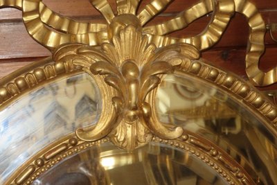 Grande specchio ovale con frontone, in legno dorato, XIX secolo.