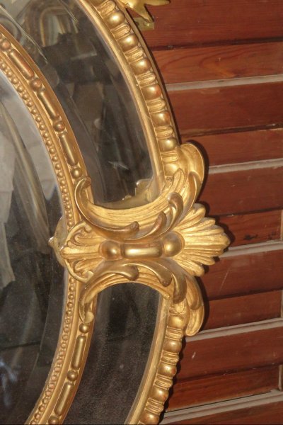 Grande specchio ovale con frontone, in legno dorato, XIX secolo.