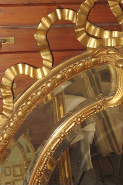 Grande specchio ovale con frontone, in legno dorato, XIX secolo.