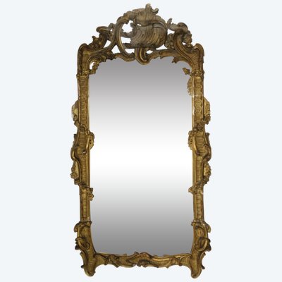 Importante specchio con frontone traforato e pannelli laterali in legno intagliato e dorato in stile rococò.