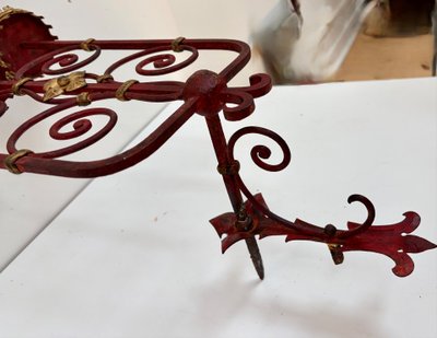 PAIR OF WROUGHT IRON CANDLE-SOCKET WALL LIGHTS, STAINED RED AND GOLD.