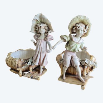 Bohemian-style porcelain figurines of children with shallow bowls, decorated with applique flowers dating to around 1900