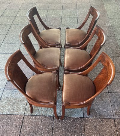 Six varnished mahogany chairs with curved backs.
