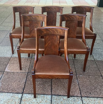 Six varnished mahogany chairs with curved backs.