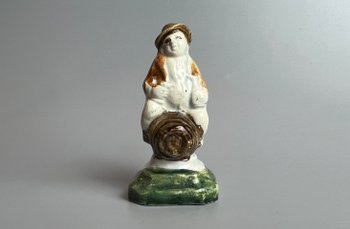 A c1790 Staffordshire pratt coloured pearlware toper figure seated on a barrel.