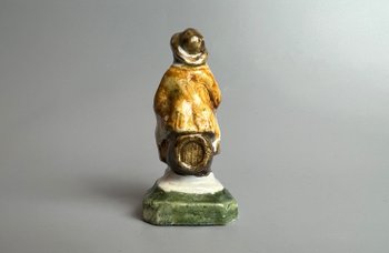 A c1790 Staffordshire pratt coloured pearlware toper figure seated on a barrel.