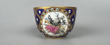 Raffinata coppa gioiello in stile Sèvres, dipinta con scene militari e trofei.