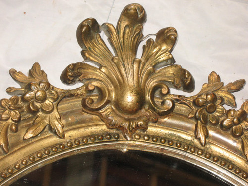 Carved oval mirror in wood and stucco gilded with leaf 19th century