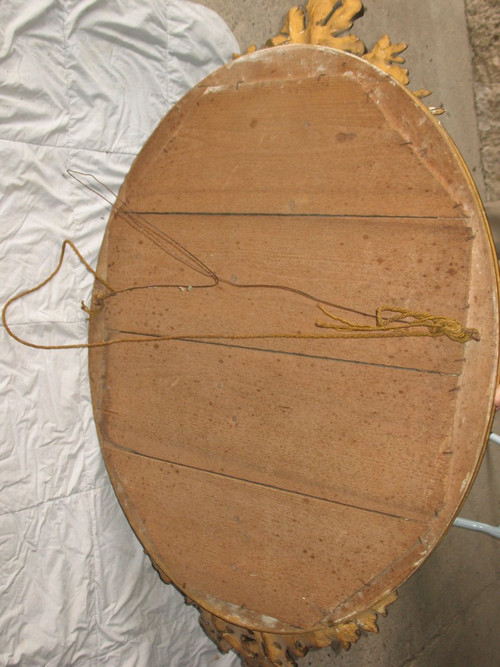 Carved oval mirror in wood and stucco gilded with leaf 19th century