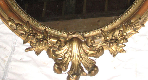 Carved oval mirror in wood and stucco gilded with leaf 19th century