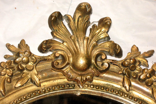 Carved oval mirror in wood and stucco gilded with leaf 19th century