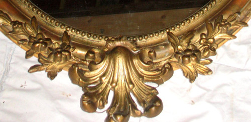 Carved oval mirror in wood and stucco gilded with leaf 19th century