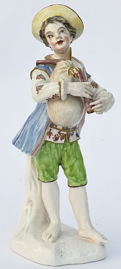 Statuette en porcelaine figurant un jeune garçon jouant de la cornemuse
