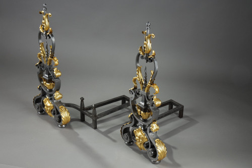 Paire de landiers en fer forgé à décor feuillagé, masque et volutes