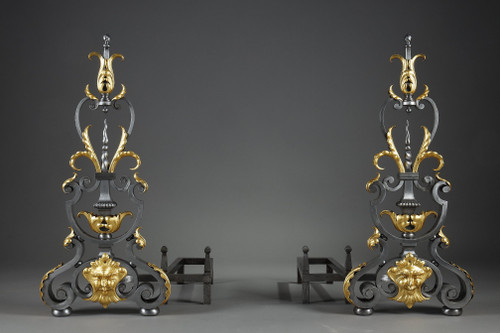 Paire de landiers en fer forgé à décor feuillagé, masque et volutes