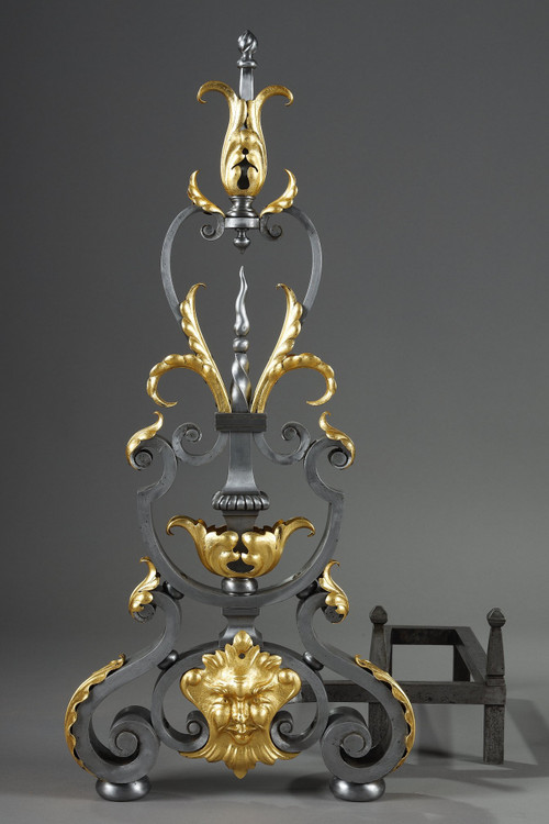 Paire de landiers en fer forgé à décor feuillagé, masque et volutes