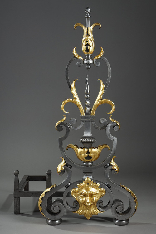 Paire de landiers en fer forgé à décor feuillagé, masque et volutes
