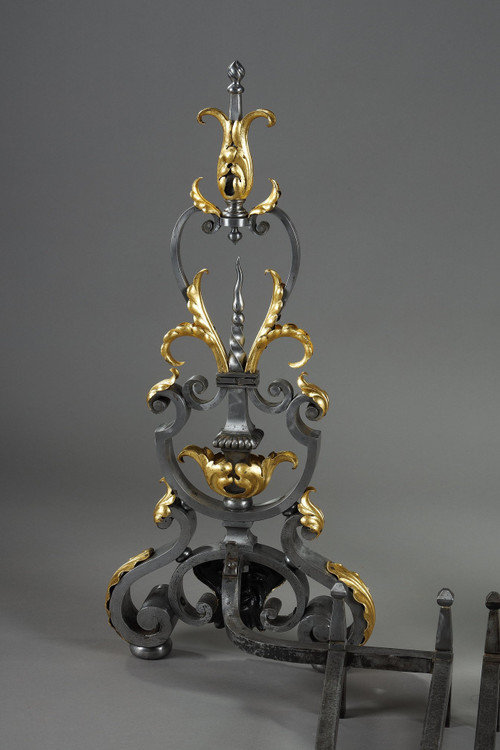 Paire de landiers en fer forgé à décor feuillagé, masque et volutes