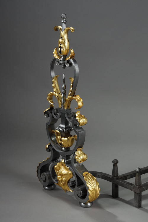 Paire de landiers en fer forgé à décor feuillagé, masque et volutes