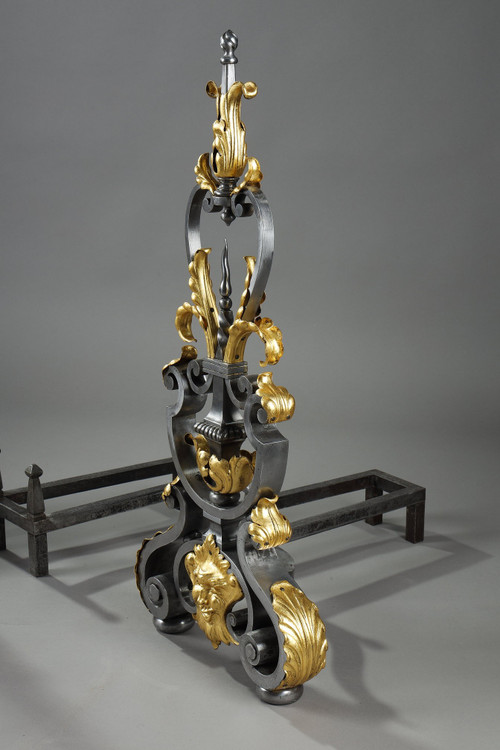 Paire de landiers en fer forgé à décor feuillagé, masque et volutes