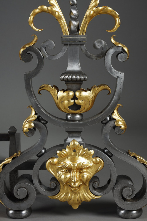 Paire de landiers en fer forgé à décor feuillagé, masque et volutes