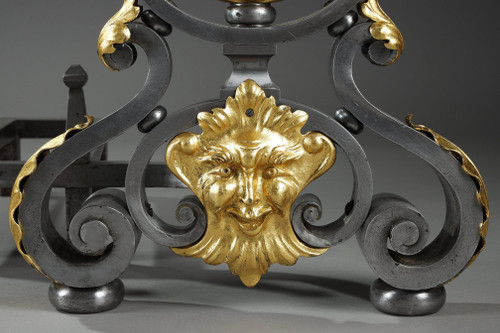 Paire de landiers en fer forgé à décor feuillagé, masque et volutes