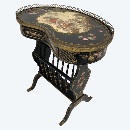Petite table de forme rognon en bois laqué noir et riches décors peints, formant porte-revues.