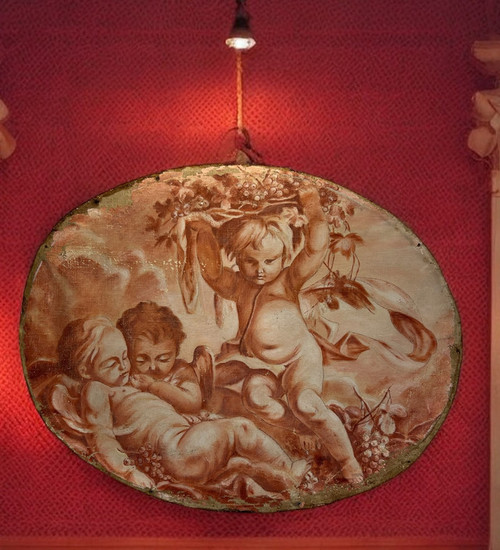OIL ON OVAL WOOD PANELING DECORATED WITH CHERUBS CARRYING A FRUIT BOWL